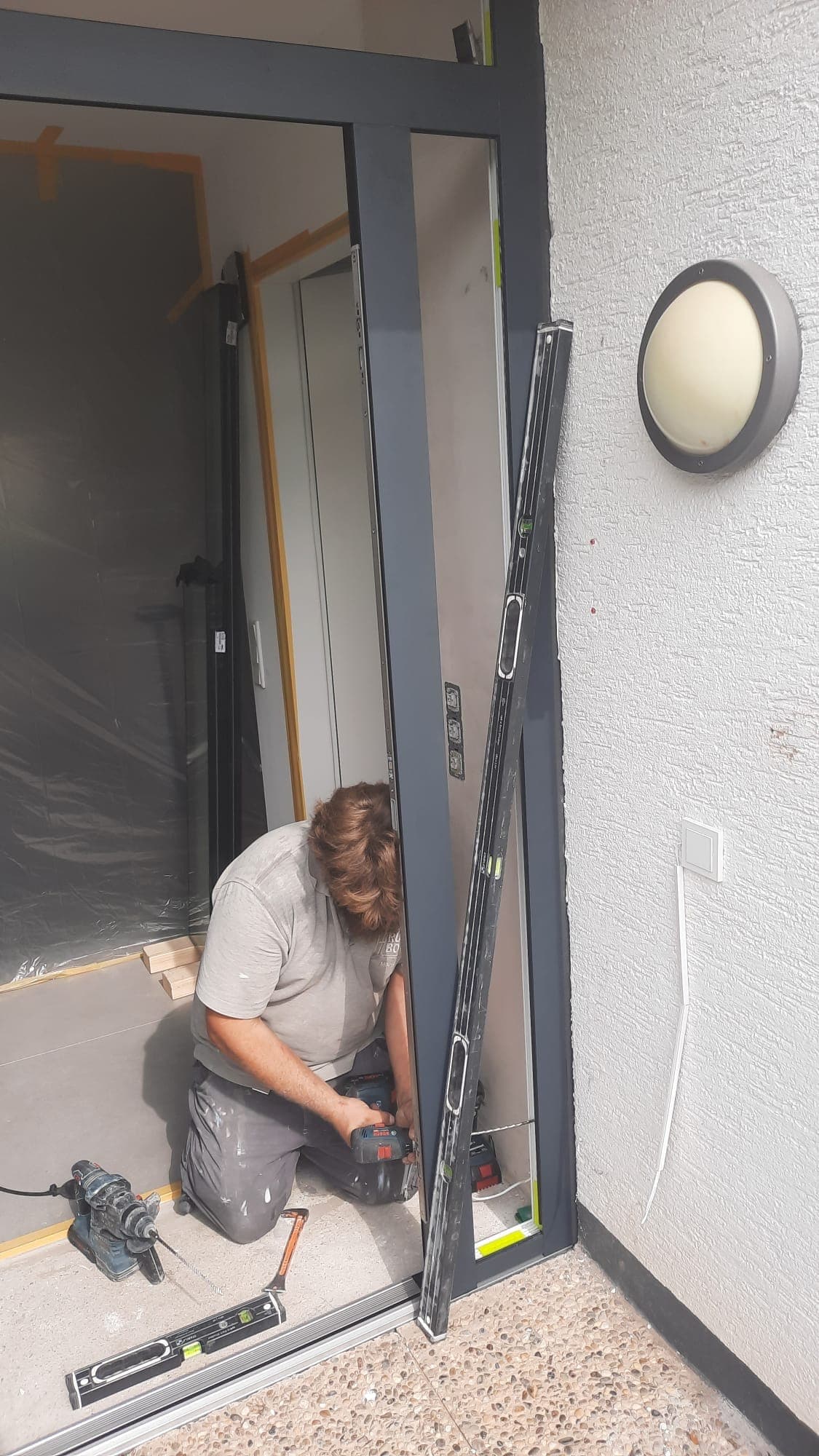 Monteur setzt eine neue Haustür ein, der Flur dahinter ist mit Abdeckvlies geschützt